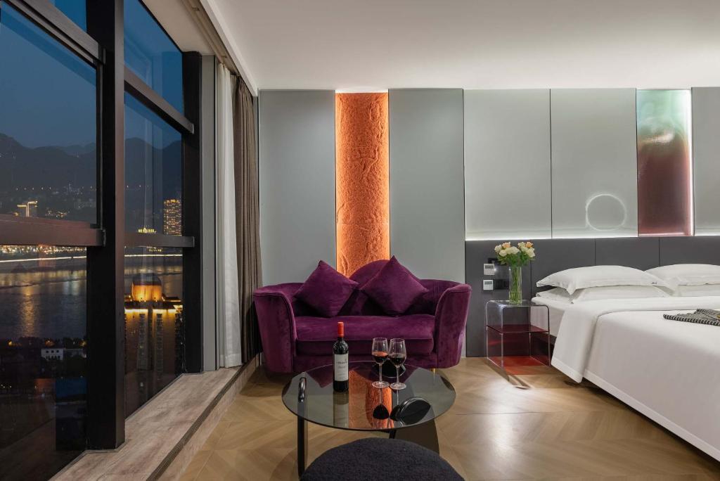 a bedroom with a bed and a purple chair at Chongqing Bairui River View Hotel- Jiefangbei Centre Branch in Chongqing