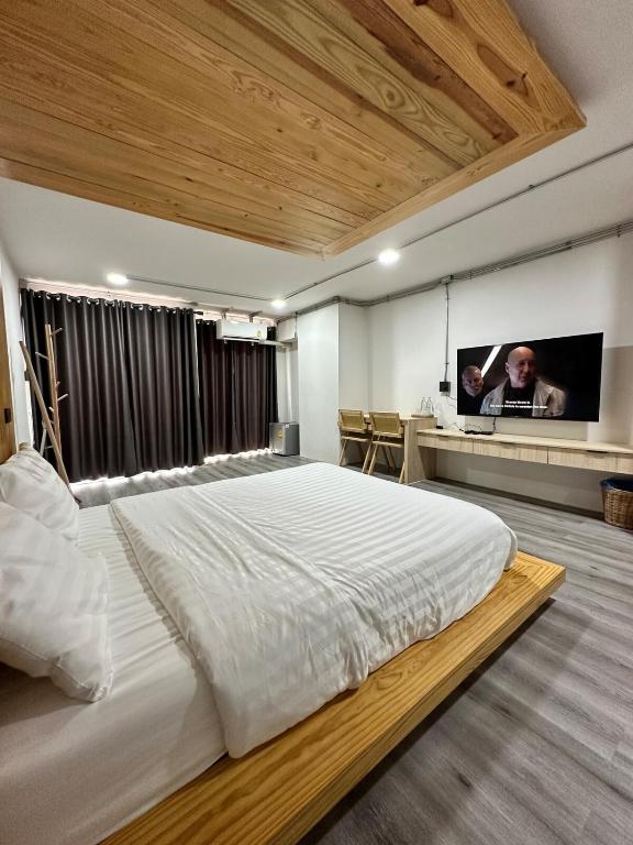 Un dormitorio con una cama grande con un televisor en la pared. en The 2nd Floor, en Lampang