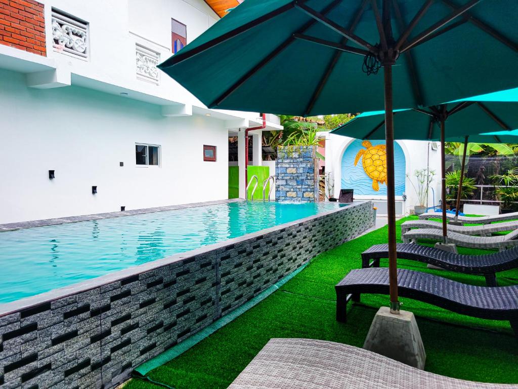 a swimming pool with two chairs and an umbrella at Sithujaya Green Mirissa in Mirissa