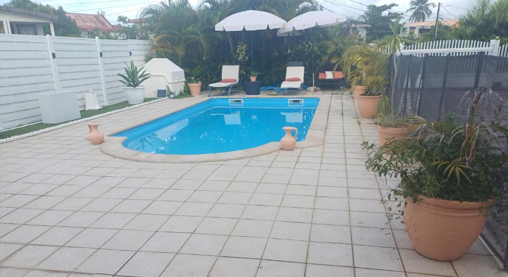 ル・ラモトンにあるCOQUET F2 CLIMATISE AVEC PISCINE AU LAMENTINの植物とパラソルのあるパティオのプール