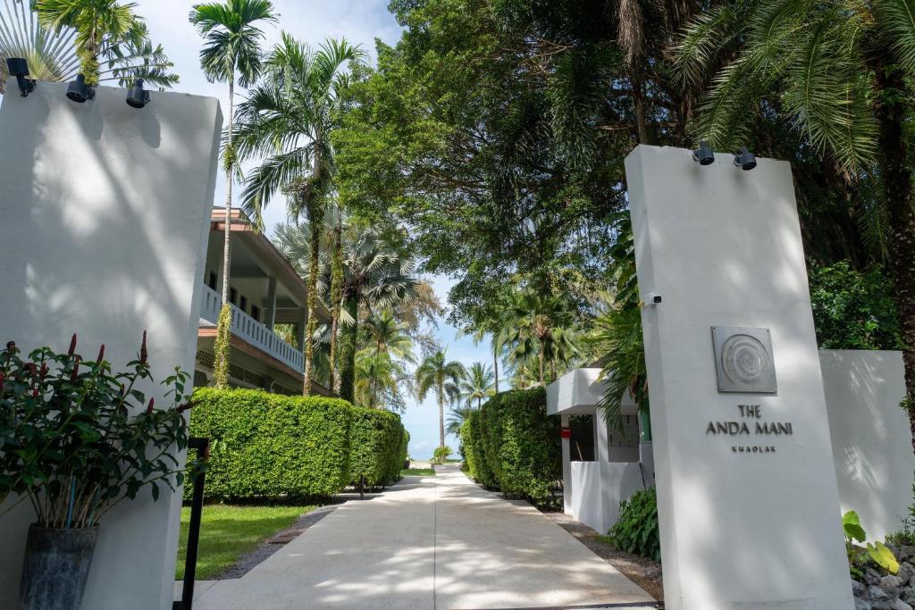 a street with palm trees and a sign that reads the now inn at The Anda Mani Khaolak Beachfront Villas - Adult only in Khao Lak