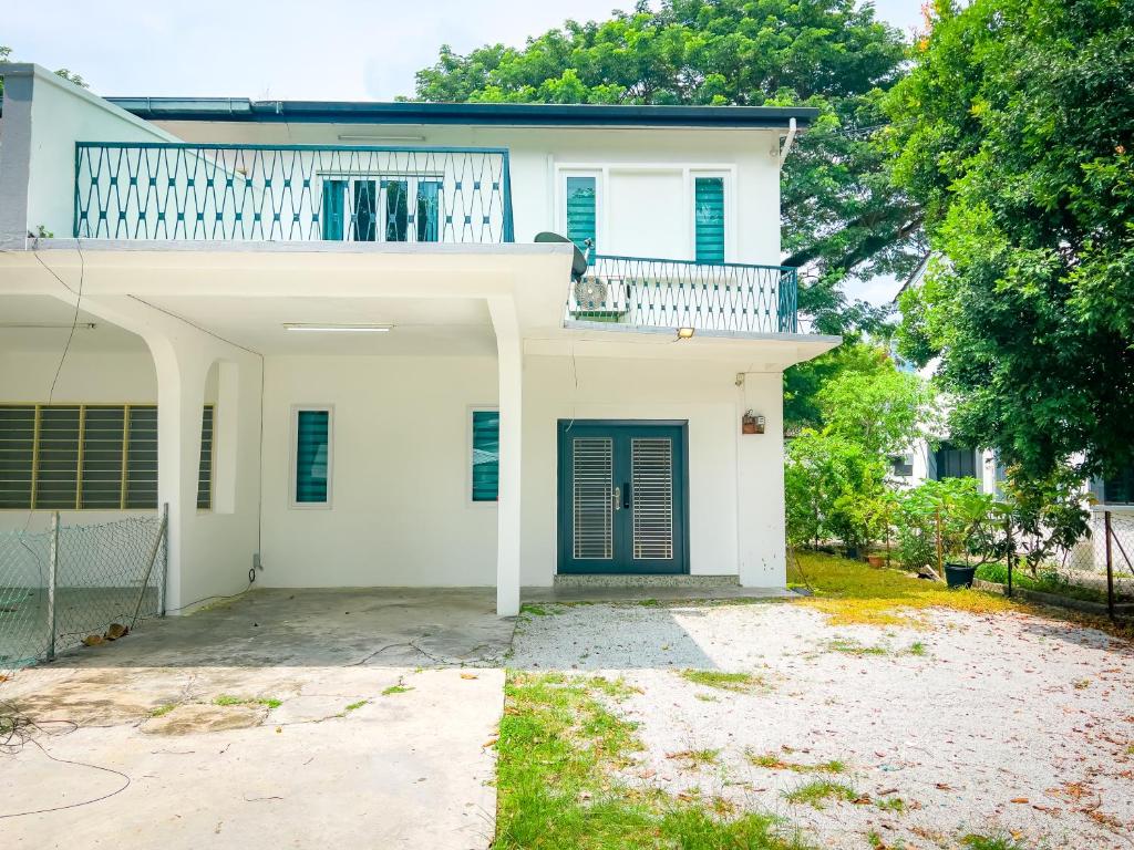 a white house with a green door and trees at Tanjung Bungah Holiday Home 4BR 20Pax 6Carpark in Tanjung Bungah