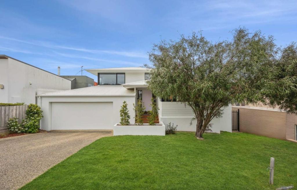 a white house with a tree and a garage at Torquay Point White-Water Retreat in Torquay