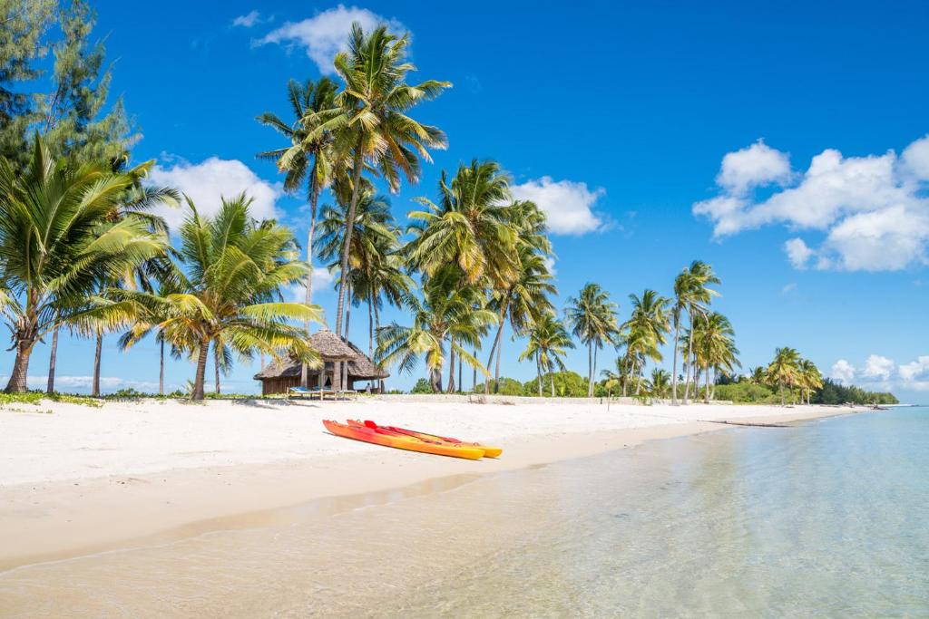 a yellow kayak on a beach with palm trees at Butiama Beach Lodge in Kilindoni