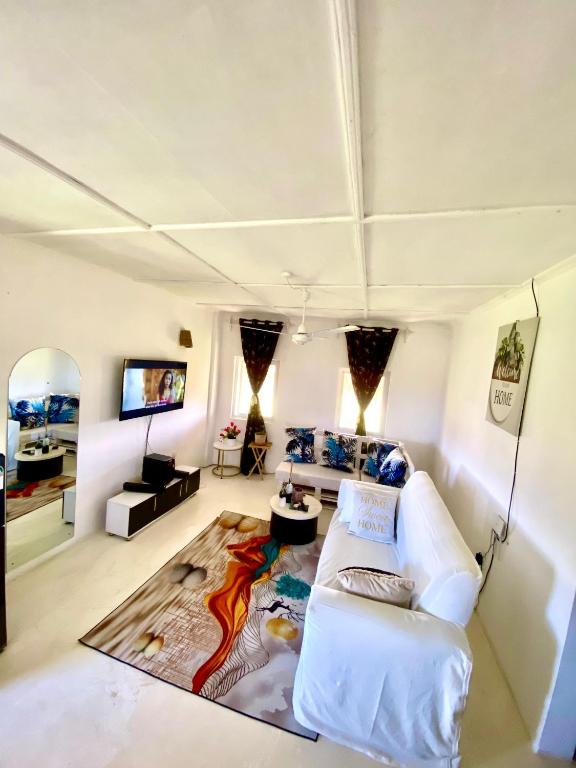a living room with a white couch and a tv at vii homes in Watamu