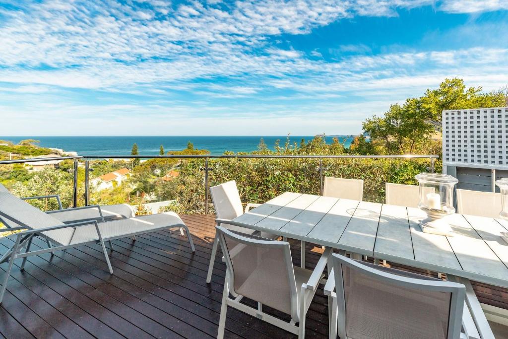 a deck with a table and chairs and the ocean at Eureka in Boomerang Beach
