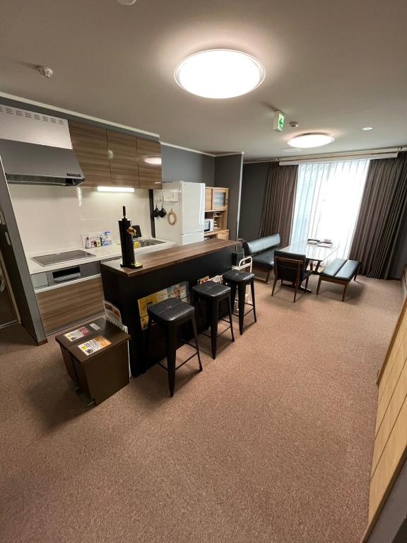 a room with a kitchen with stools and a counter at Yasuragi-KAWAGOE 2F in Kawagoe
