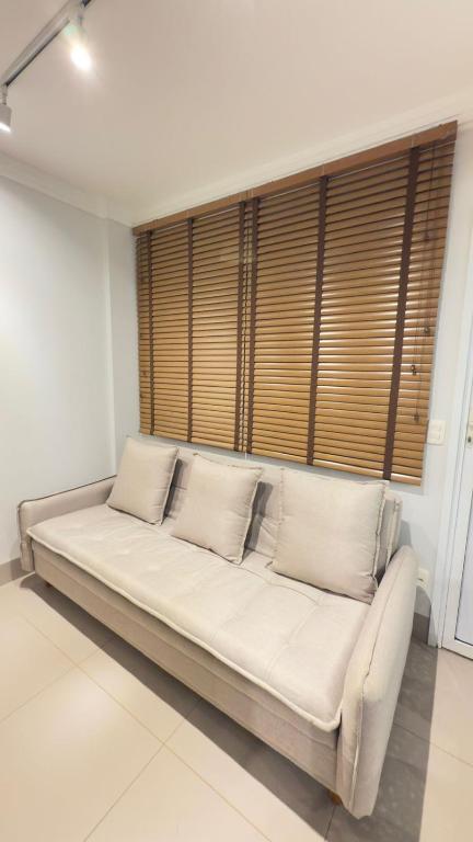a white couch in a room with a large window at Studio Inn Rami in Uberlândia