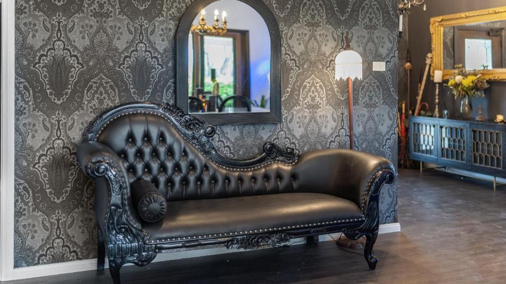 Un sofá de cuero en una habitación con un espejo en Gothic Manor, en Luskintyre