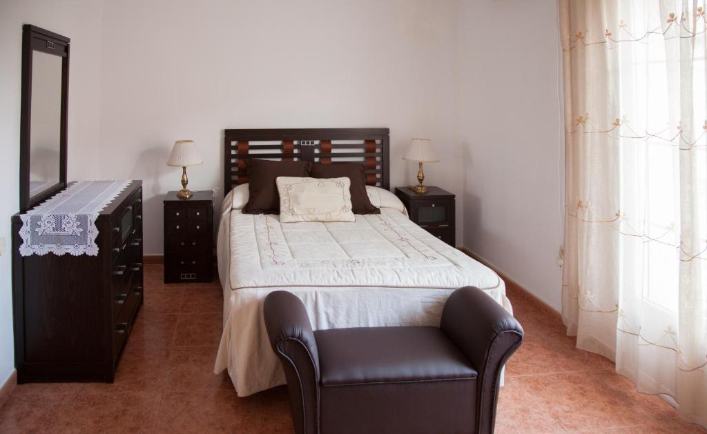 a bedroom with a large bed and a chair at Casa Rural Marchena in Navahermosa