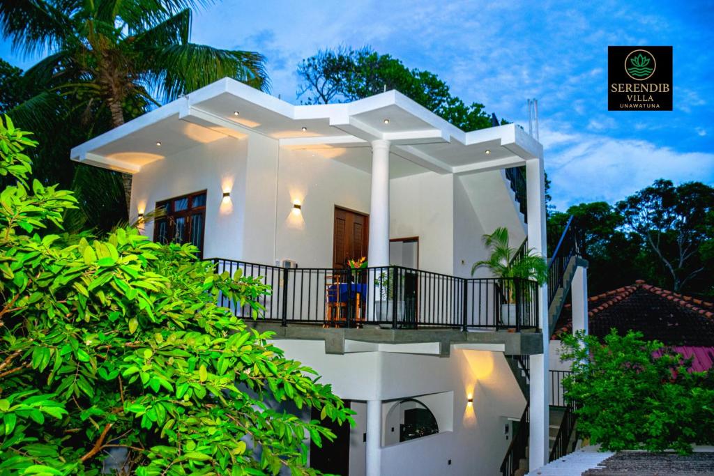 une maison blanche avec un balcon et des arbres dans l'établissement Serendib villa unawatuna, à Unawatuna