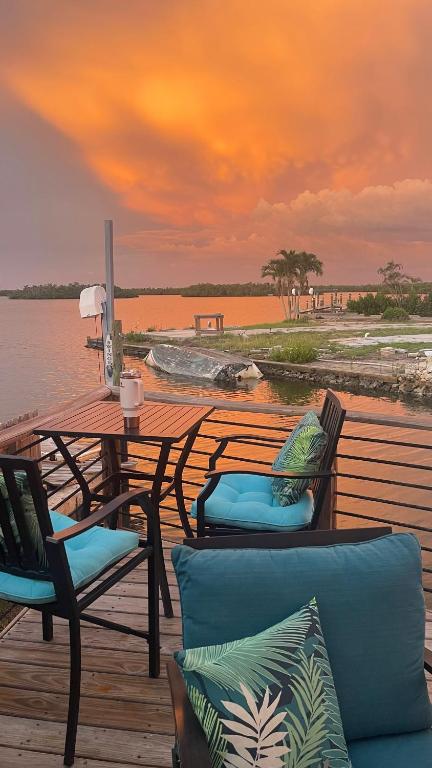 a wooden deck with a table and chairs on the water at Dolphin House Rental Vacation in Fort Myers Beach