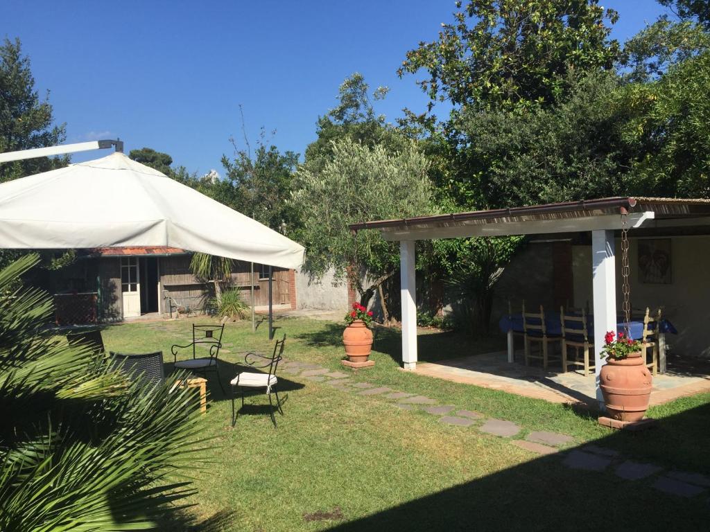 a patio with a white umbrella and chairs in a yard at Il Giardino segreto Forte dei Marmi in Forte dei Marmi