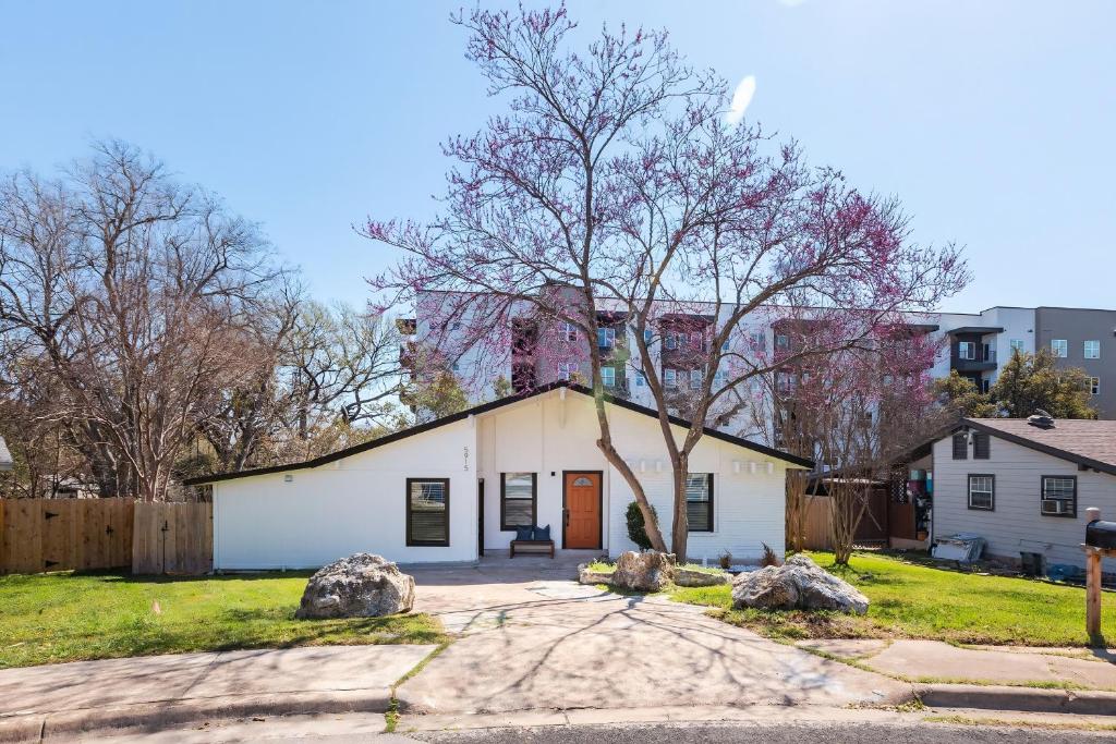 a white house with a tree in the yard at Big Group, Affordable, Comfy, Big Beds, Rain Shower, SoCO Eateries in Austin