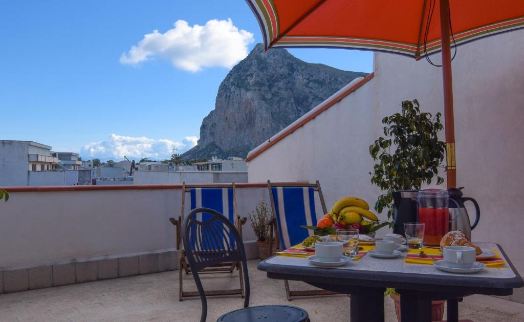 a table with an umbrella on a balcony with a mountain at B&B Alighieri 21 in San Vito lo Capo
