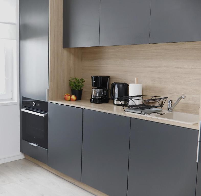 - une cuisine avec un comptoir, un évier et une cuisinière dans l'établissement Apartament w Centrum Słupska z parkingiem, à Słupsk