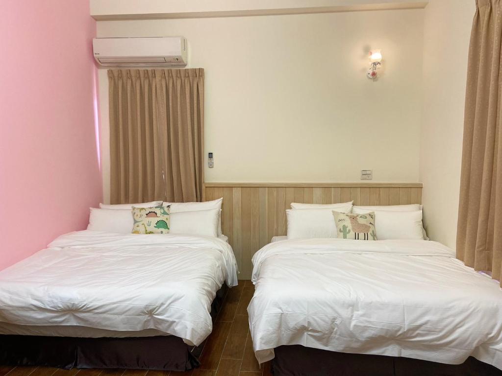 two beds sitting next to each other in a room at 虎尾五八五民宿 in Huwei