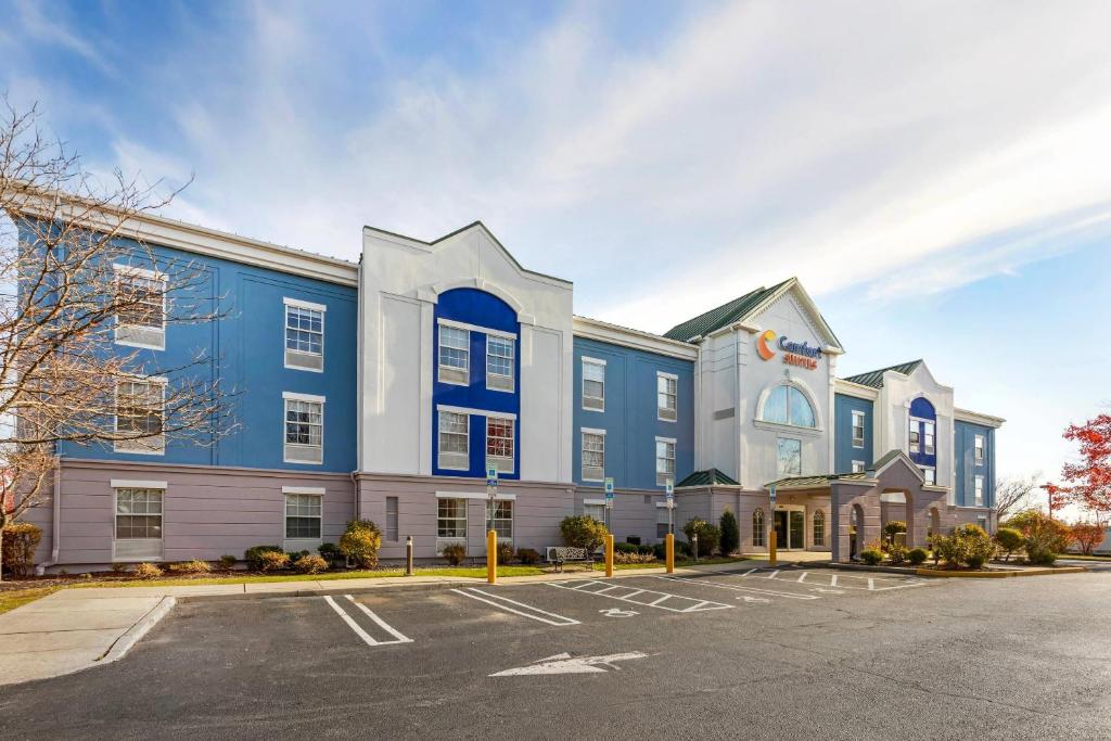 a blue and white building with a parking lot at Comfort Suites East Brunswick - South River in East Brunswick