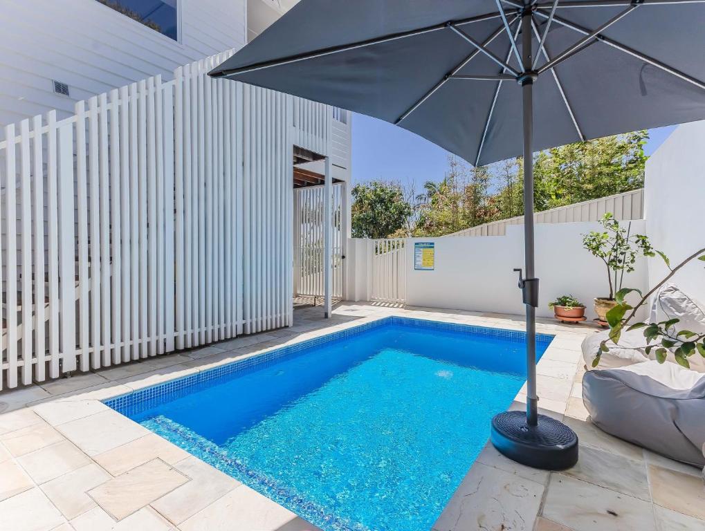 Una sombrilla junto a una piscina en High Tide 4BR 3 level house Ocean views & Pool, en Kingscliff