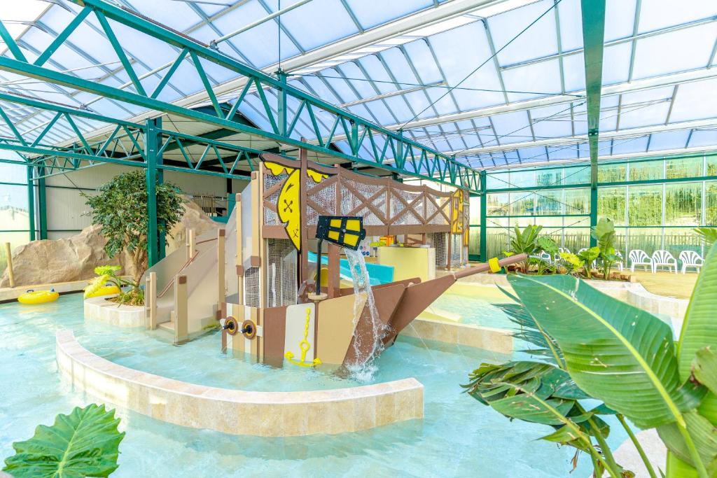 a pool with a water slide in a building at Camping Le Parc de Paris in Villevaudé