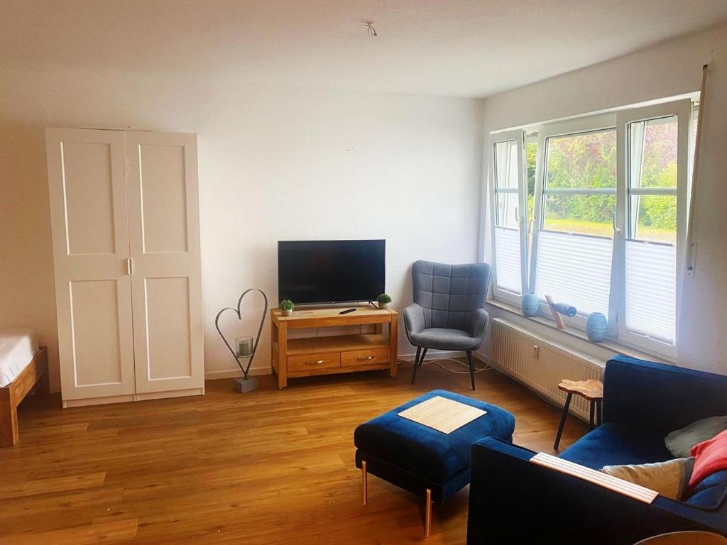 a living room with a flat screen tv and a chair at Comfort Apartment in Rösrath in Rösrath