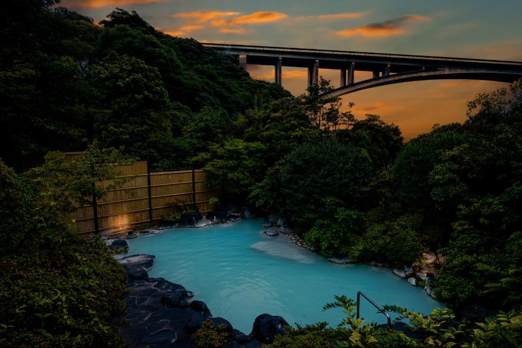 a river with a bridge in the background at Okamotoya in Beppu