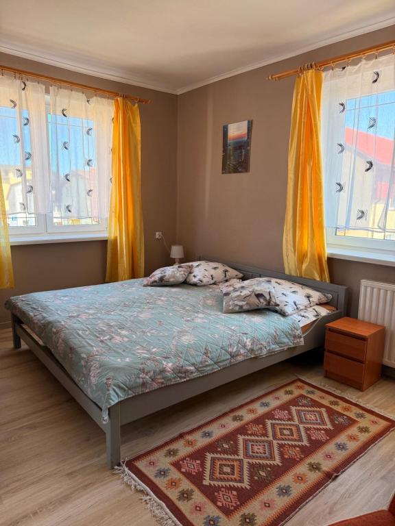 a bedroom with a bed with yellow curtains and a rug at Dom wczasowy Max in Darłowo