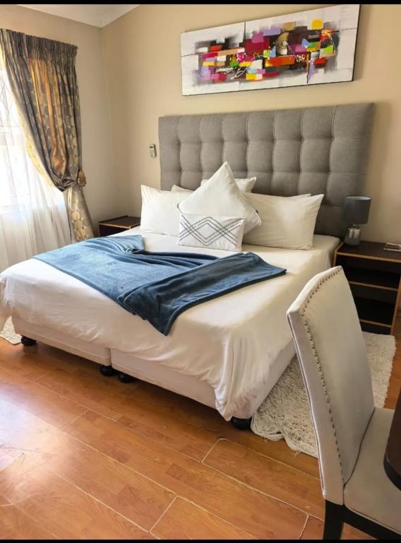 a bedroom with a large bed and a chair at Not Today Guest Lodge in Mthatha