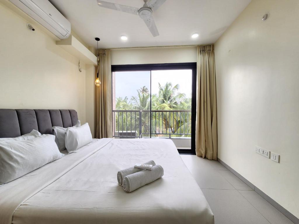 a bedroom with a large bed and a large window at Peaceful Candolim 2BHK Apartment - Family Stay, Scenic View, Pool in Candolim