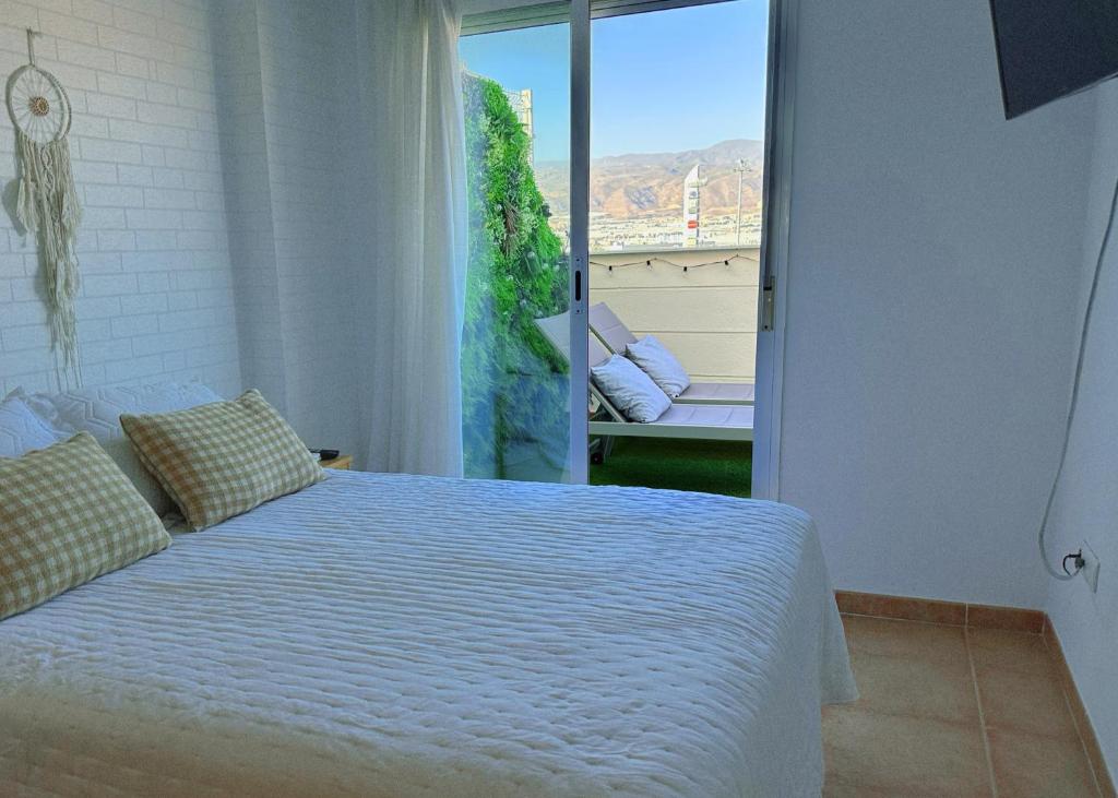 a bedroom with a bed and a large window at Ático junto al Teatro AUDITORIO de Roquetas de Mar in Roquetas de Mar