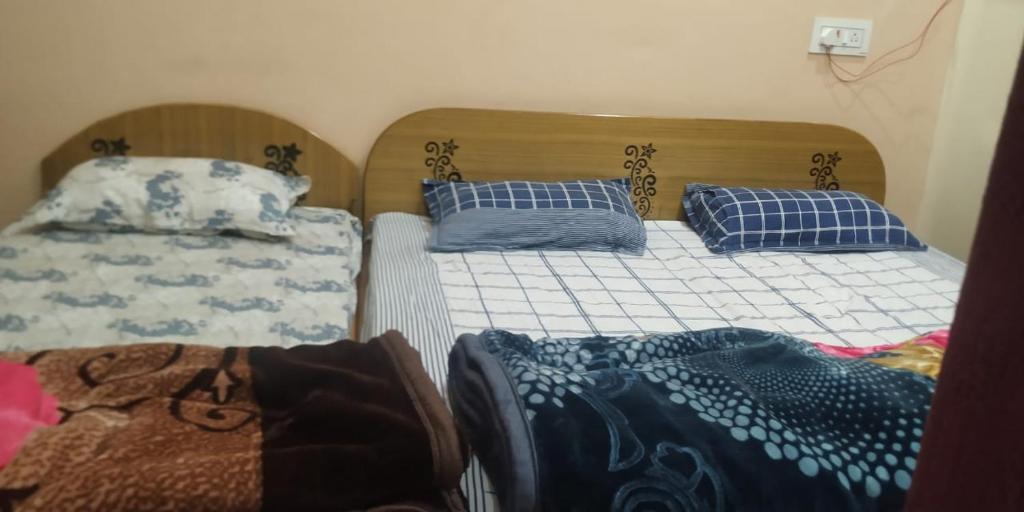 two beds with blue pillows on them in a room at Anant Paying Guest house in Ayodhya