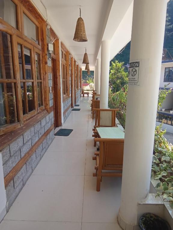 um corredor de um edifício com mesas e cadeiras em Hotel Purnima by smugglers hotels em Kasol