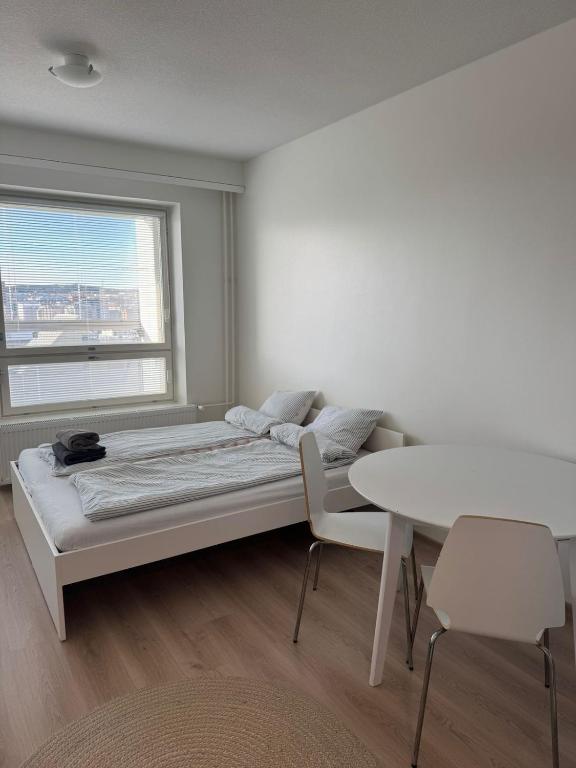 a bedroom with a bed and a table and a window at RD Apartments - Areenan Lumo in Tampere