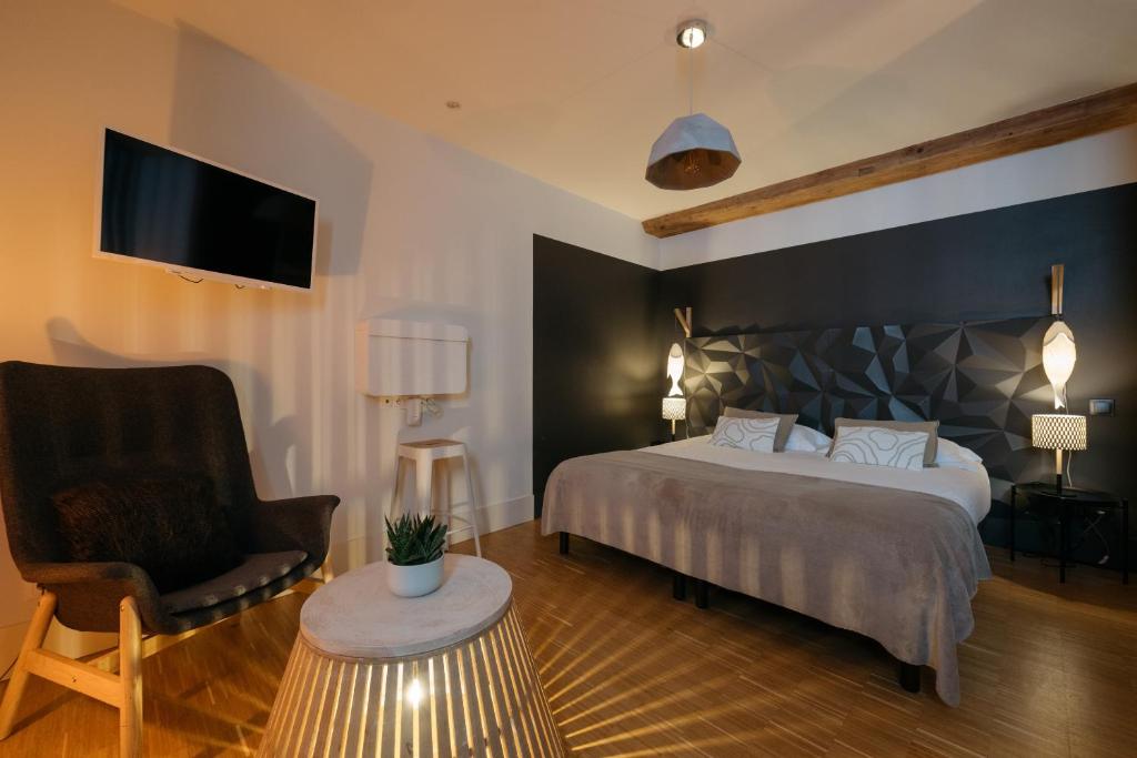 - une chambre avec un lit, une chaise et une télévision dans l'établissement Appart Hotel Eugenie, à Louhans