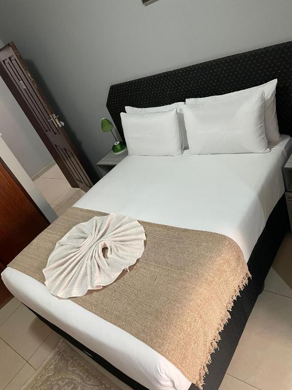 a bedroom with a bed with a large white bedspread at The Siblings Legacy Hotel in Palatswe