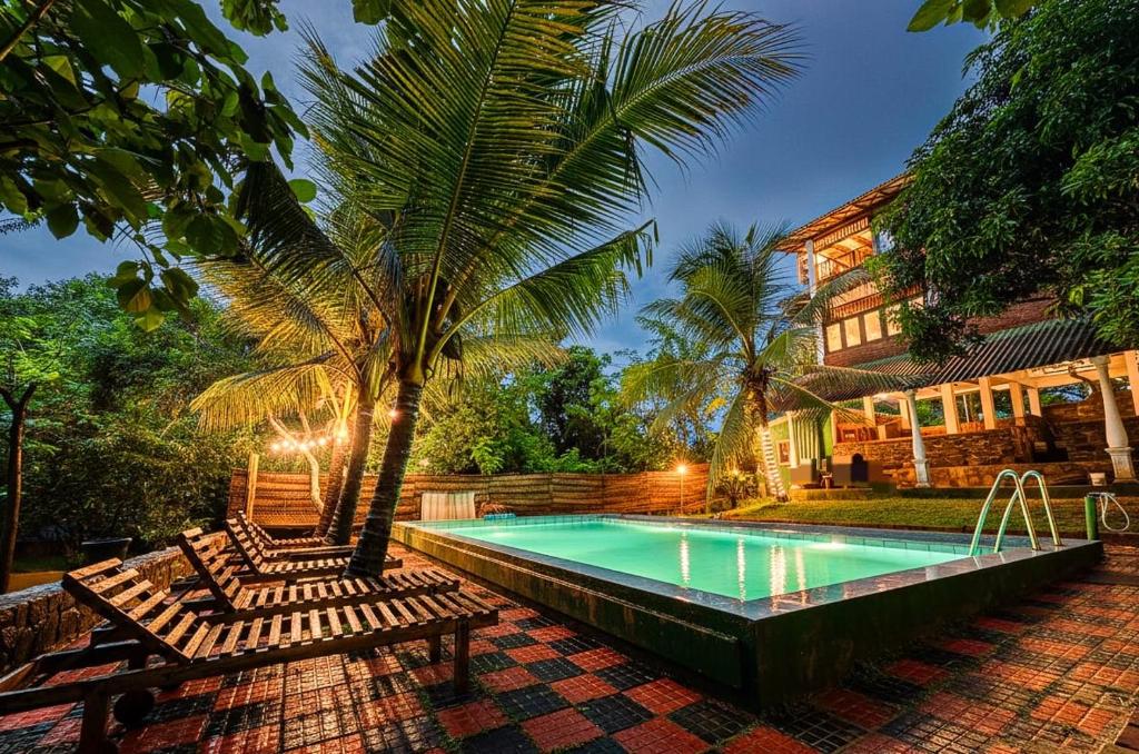 a pool with chairs and a palm tree next to a house at Verdant Hill Villa in Tangalle