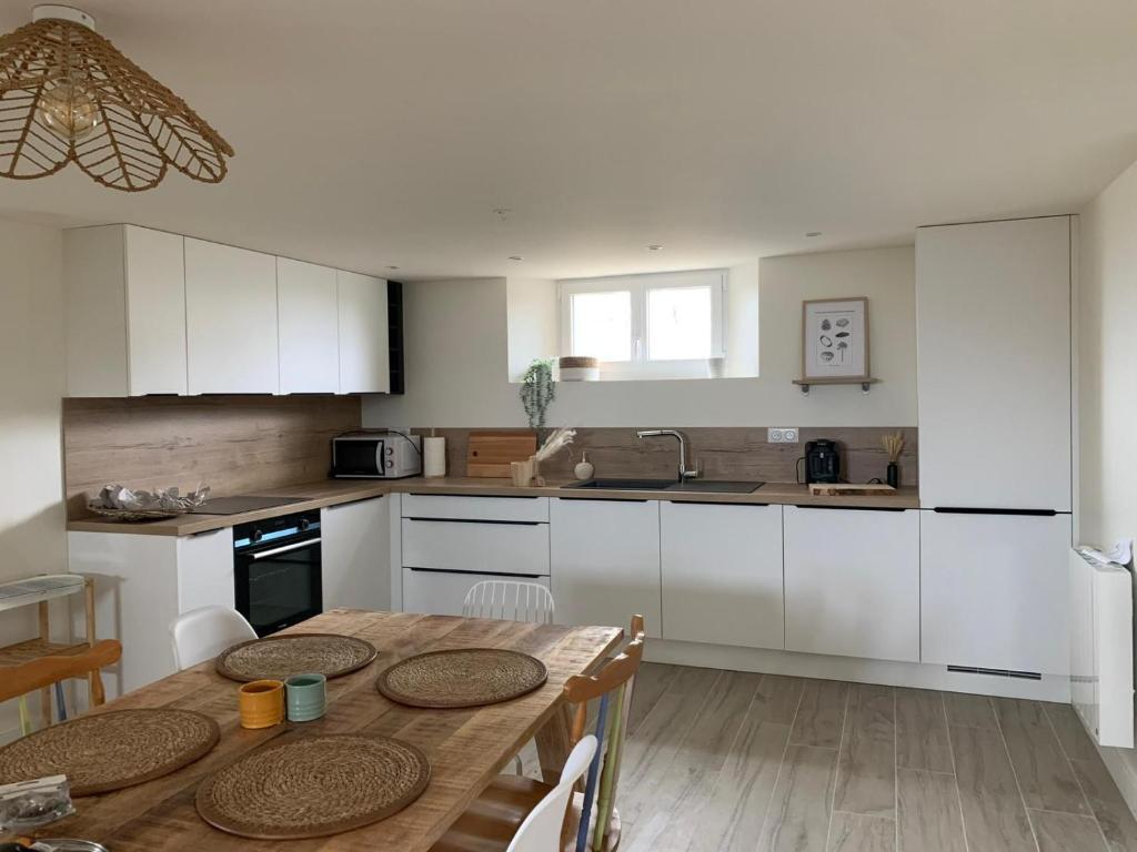 a kitchen with white cabinets and a wooden table at Séjour Entre Océan et Centre-Ville in Hossegor