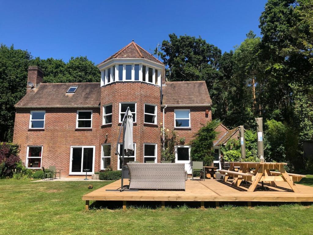 - un grand bâtiment en briques avec une table de pique-nique devant dans l'établissement Poole Manor House, à Lytchett Matravers