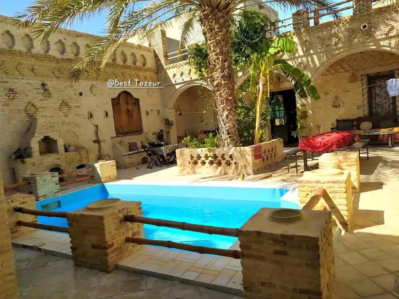 a pool in a courtyard with a palm tree at Villa Dar El Bey in Tozeur