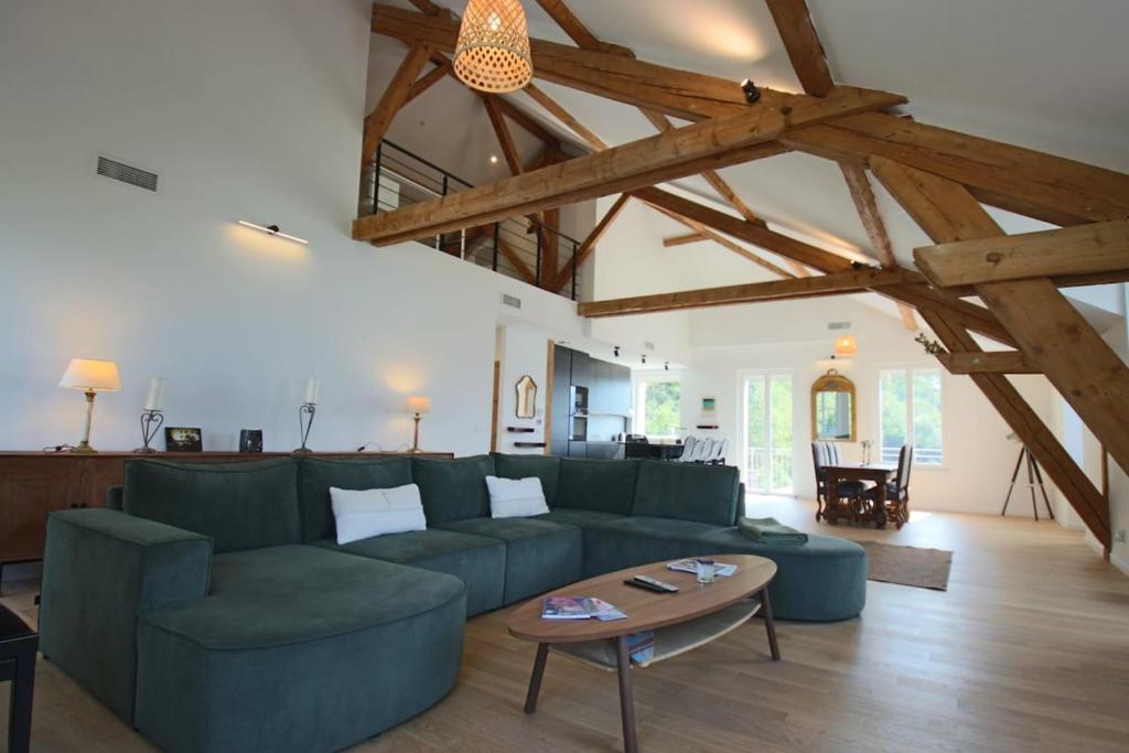 a living room with a green couch and a table at Appartement T5 145m2 4 chambres, vue lac climatisé in Tresserves