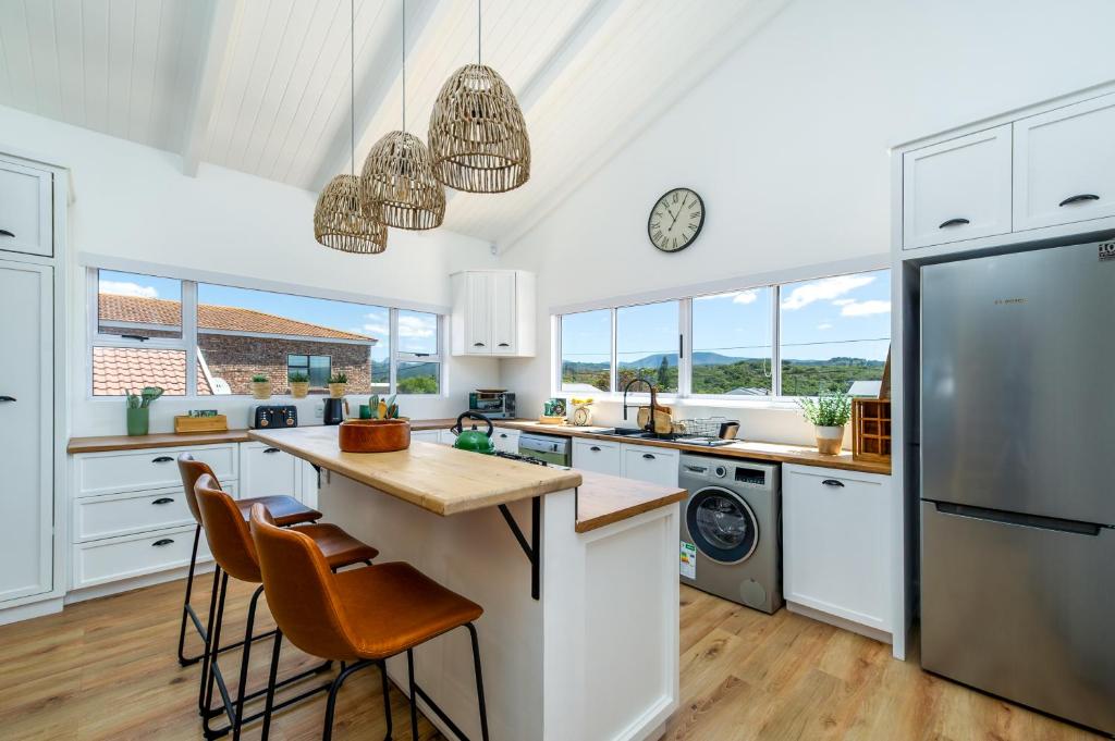 a kitchen with white cabinets and a counter with stools at The White House - Kleinkrantz in Wilderness