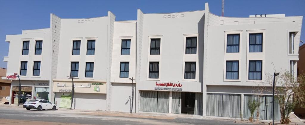 a white building on the corner of a street at رؤوم إن للشقق المخدومة Raoum Inn Serviced Apartments-Shaqraa in Shaqra