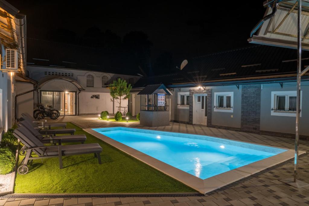 a swimming pool in a backyard at night at Oaza Mira LAZE in Nova Gradiška
