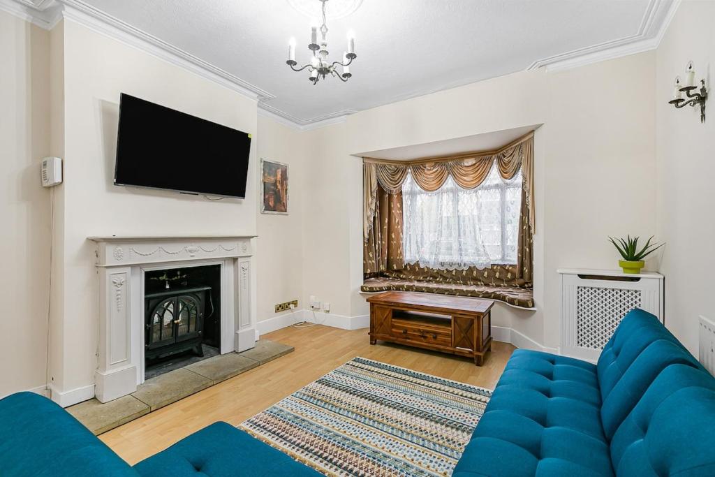 ein Wohnzimmer mit einer blauen Couch und einem Kamin in der Unterkunft Spacious charming house near Heathrow in Feltham