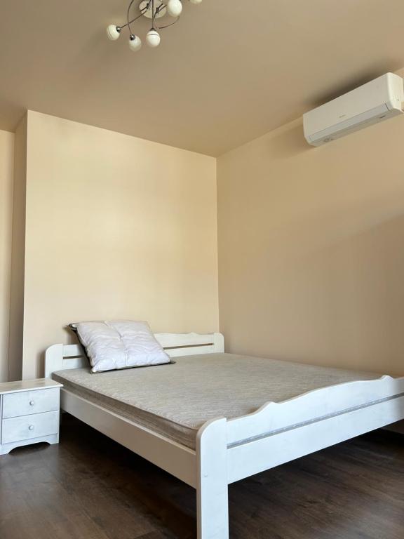 a bedroom with a white bed and a white wall at Szántó Prime Residence in Szolnok
