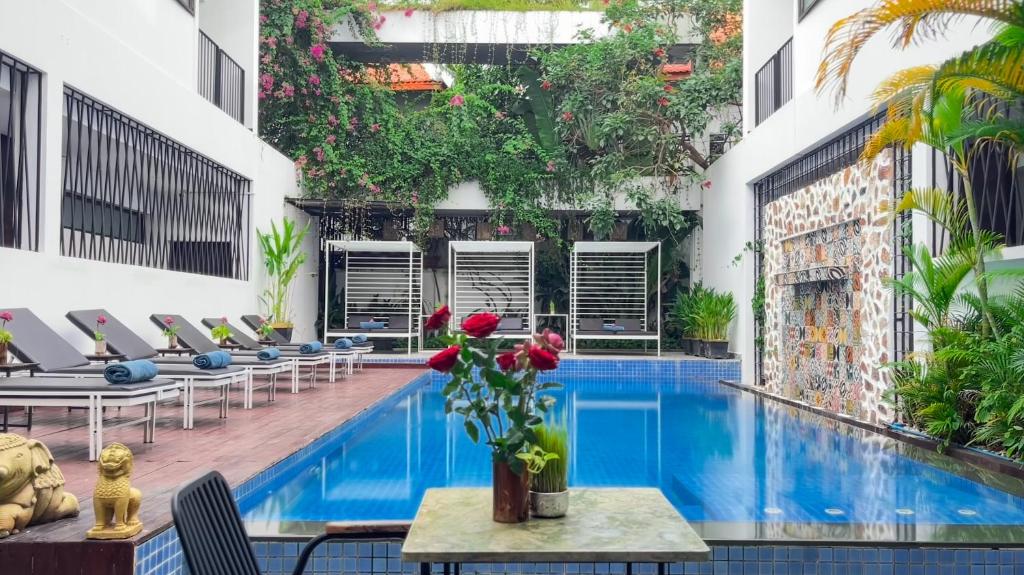 Una piscina en un edificio con sillas y un jarrón de flores. en The Calm Oasis, en Siem Reap
