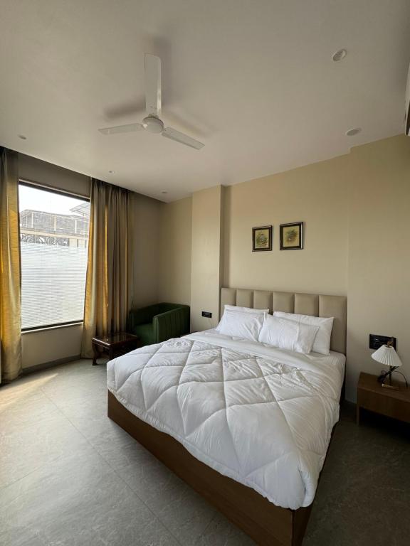 a bedroom with a large white bed and a window at Modern Hotel Restaurant and Bar in Mathura