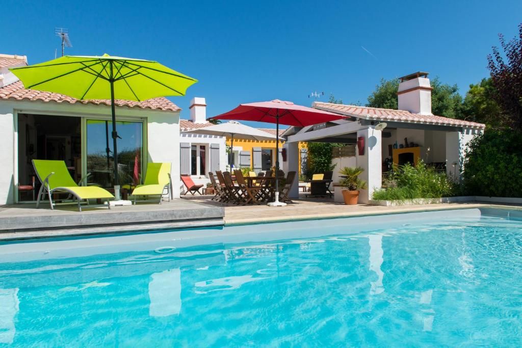 a house with a swimming pool with chairs and umbrellas at Les Yeux Bleus Bed & Breakfast in Noirmoutier-en-l'lle