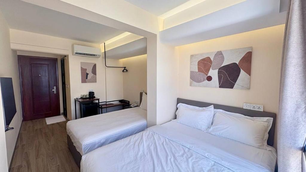 a hotel room with two beds and a mirror at The Guesthouse By SH in Phnom Penh