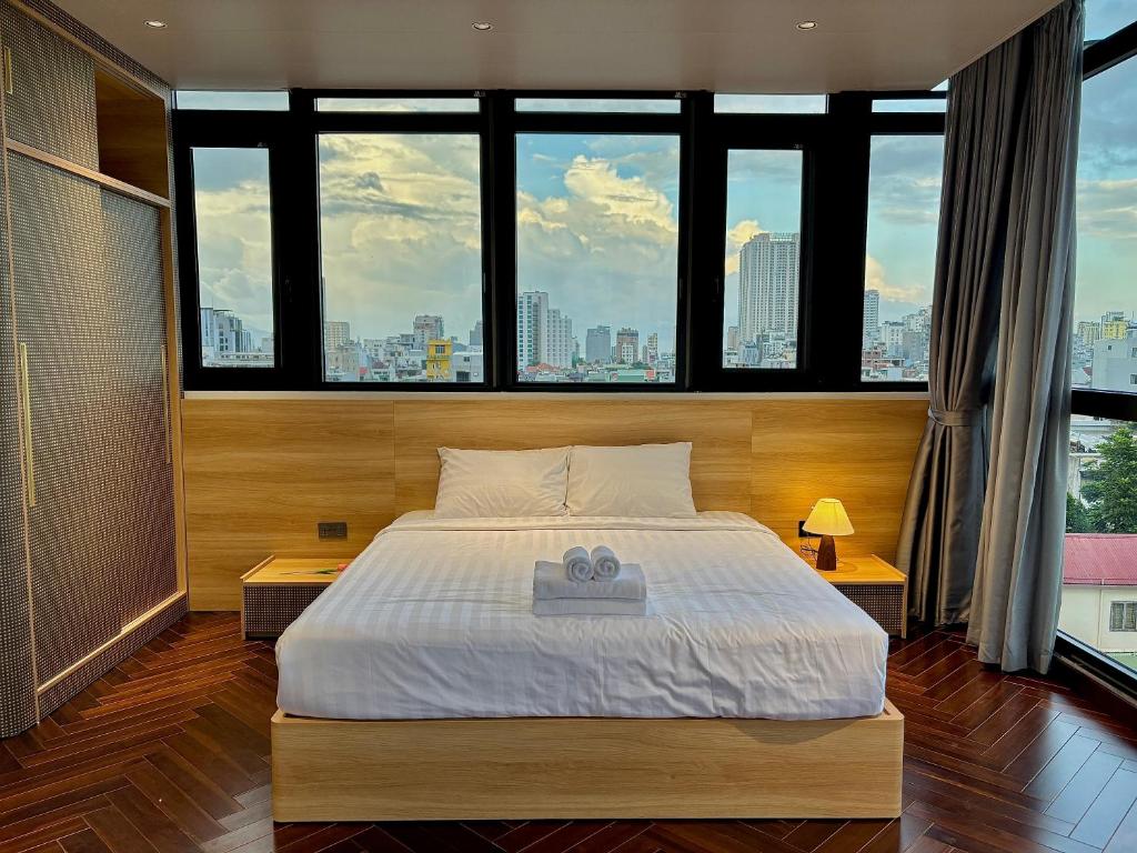 a bedroom with a large bed and large windows at MAIA Hotel & Apartment Danang in Da Nang